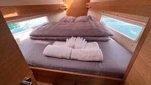 Un dormitorio pequeño y bien iluminado con cama, almohadas y una toalla doblada con cuidado.