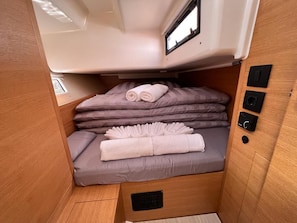 A compact, well-lit interior with a bed, pillows, and a control panel.