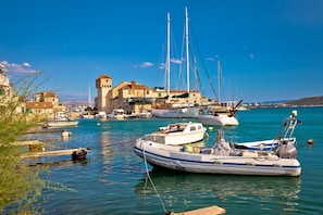 A harbor with boats, a historic building with a tower, and calm waters.