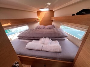 A compact, well-lit bedroom with a bed, pillows, and a neatly folded towel. - Sun-Kissed Sailing Adventure in Split, Croatia (Kaštel Gomilica)