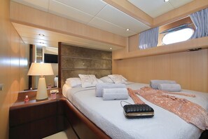 A modern, well-lit bedroom with a large bed, a bedside table with a lamp, and a window with curtains. - Sun-Kissed Sailing Adventure in Split, Croatia (Kaštel Gomilica)