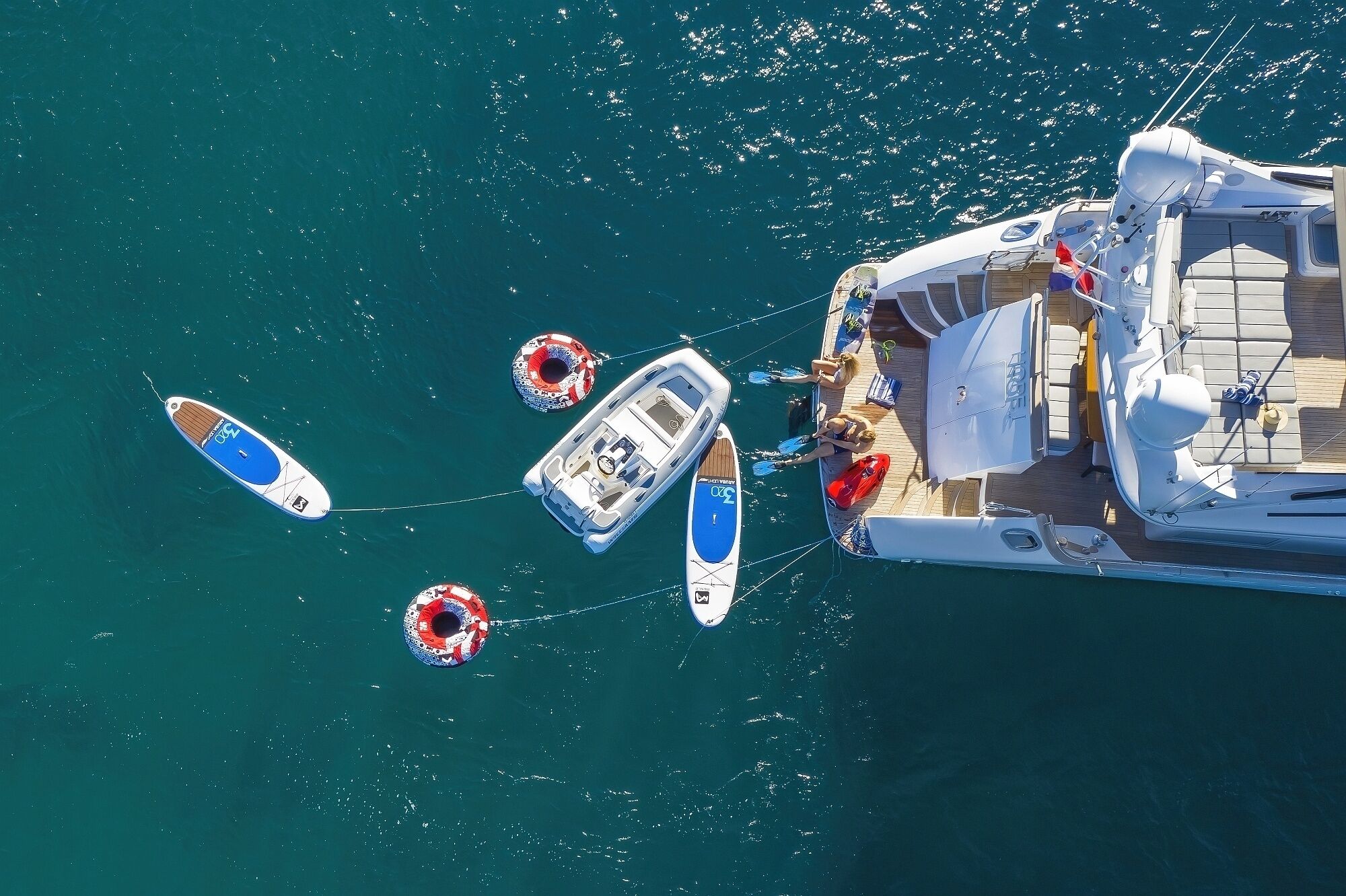 Uno yacht ormeggiato in una marina, con diverse imbarcazioni più piccole fissate nelle vicinanze.