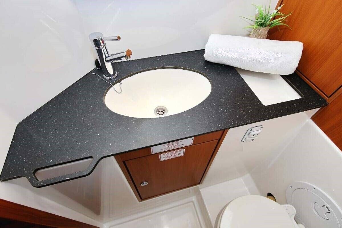 A compact bathroom with a sink, toilet, and a small plant.