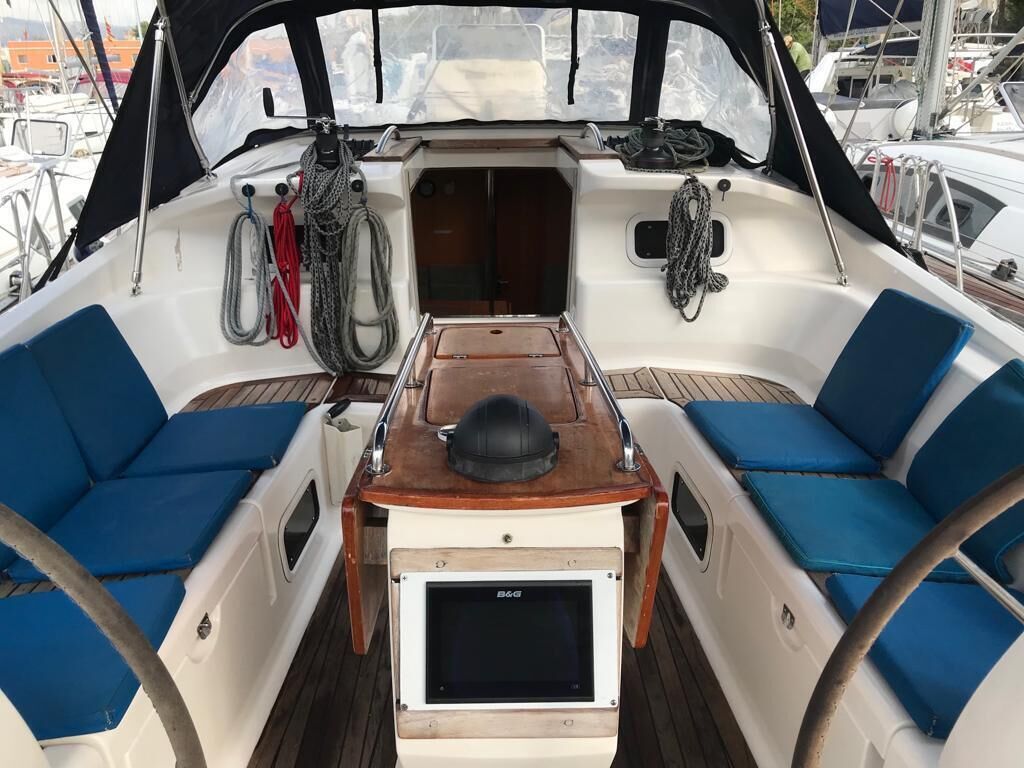 A boat's interior with two blue cushioned seats, a wooden table, and a steering wheel.