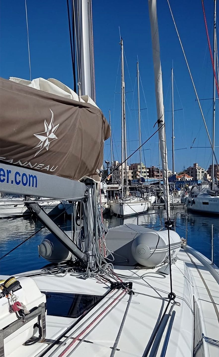 En småbåtshamn med flera segelbåtar förtöjda, vissa med överbyggda områden och andra där masten syns.