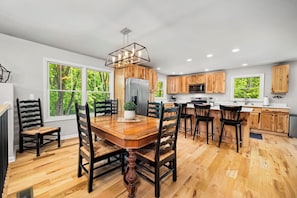 A modern kitchen with wooden cabinets, a central island, and a dining area with a wooden table and chairs.