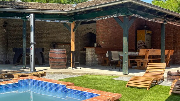 A covered outdoor area with a pool, wooden furniture, and a brick building. - Beautiful home in Batina with private swimming pool, can be inside or outside (Batina)