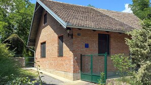 A brick building with a sloped roof, a green gate, and a sign indicating a rating. - Beautiful home in Batina with private swimming pool, can be inside or outside (Batina)