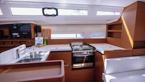 A compact kitchen with a sink, stove, and storage cabinets. - Sun-Kissed Sailing Adventure in Split, Croatia (Kaštel Gomilica)