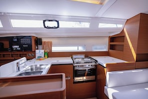 A compact kitchen with a sink, stove, and storage cabinets. - Sun-Kissed Sailing Adventure in Split, Croatia (Kaštel Gomilica)