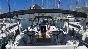 Een zeilboot met twee roerposities, een hut met uitzicht op de jachthaven, en de naam 'Sailing Forever' op de romp.