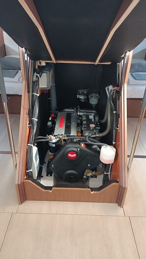 Ein kleiner Maschinenraum mit sichtbarem Motor, verschiedenen Schläuchen und einer Bedienkonsole.