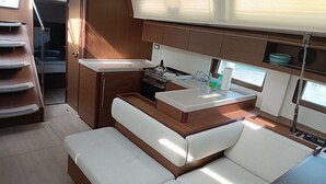 Une cuisine compacte équipée d’une cuisinière, d’un évier et de placards de rangement. On y trouve également un banc avec des coussins et une petite fenêtre qui laisse entrer la lumière naturelle.