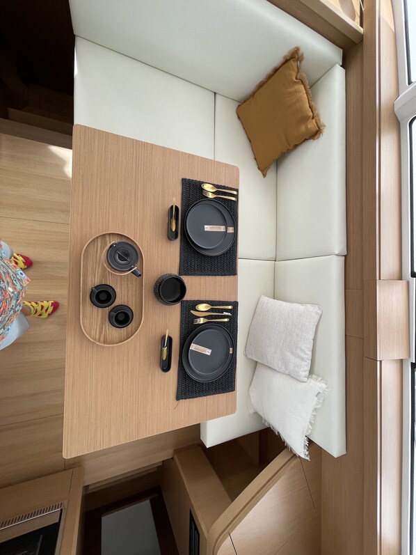 A compact living area with a dining table set for two, a sofa, and a small window.