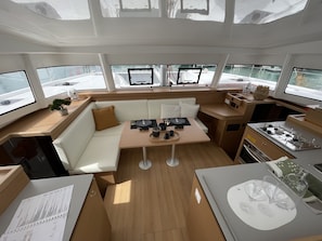 A boat interior with a dining area, seating, and a kitchen.