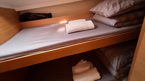 Una cama litera con colchón, almohadas y toallas dobladas.