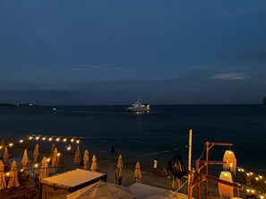 A beachside view with a boat on the water, umbrellas, and a wooden structure. - Getway with an incredible pool Marina Bay view! (Cabo San Lucas)