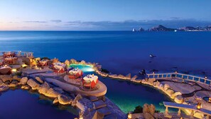 Ein Resort mit Außenrestaurants, einem Pool und Blick auf das Meer und ferne Berge.