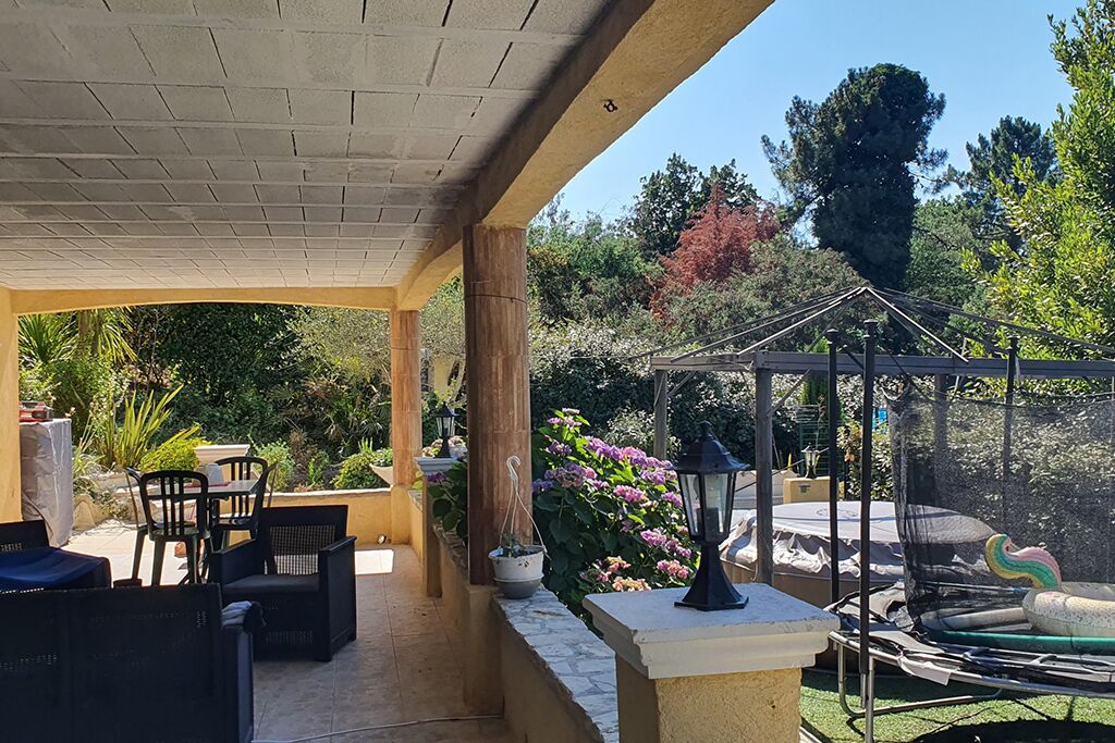 A covered patio area with outdoor furniture, a pergola, and a swing set.