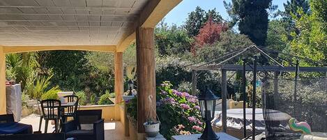 A covered patio area with outdoor furniture, a pergola, and a swing set.