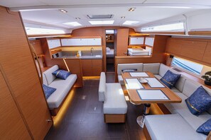 A compact, well-lit interior with a kitchenette, seating area, and a small dining table. - Sun-Kissed Sailing Adventure in Split, Croatia (Kaštel Gomilica)