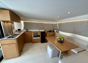 Una cocina compacta con electrodomésticos integrados, un comedor con mesa y asientos, y un ventanal con cortinas.