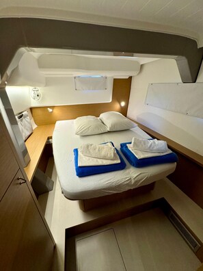 A compact cabin with a bed, a small table, and a storage cabinet. - Dubrovnik Delight: A Sun-Kissed Sailing Experience (Komolac)