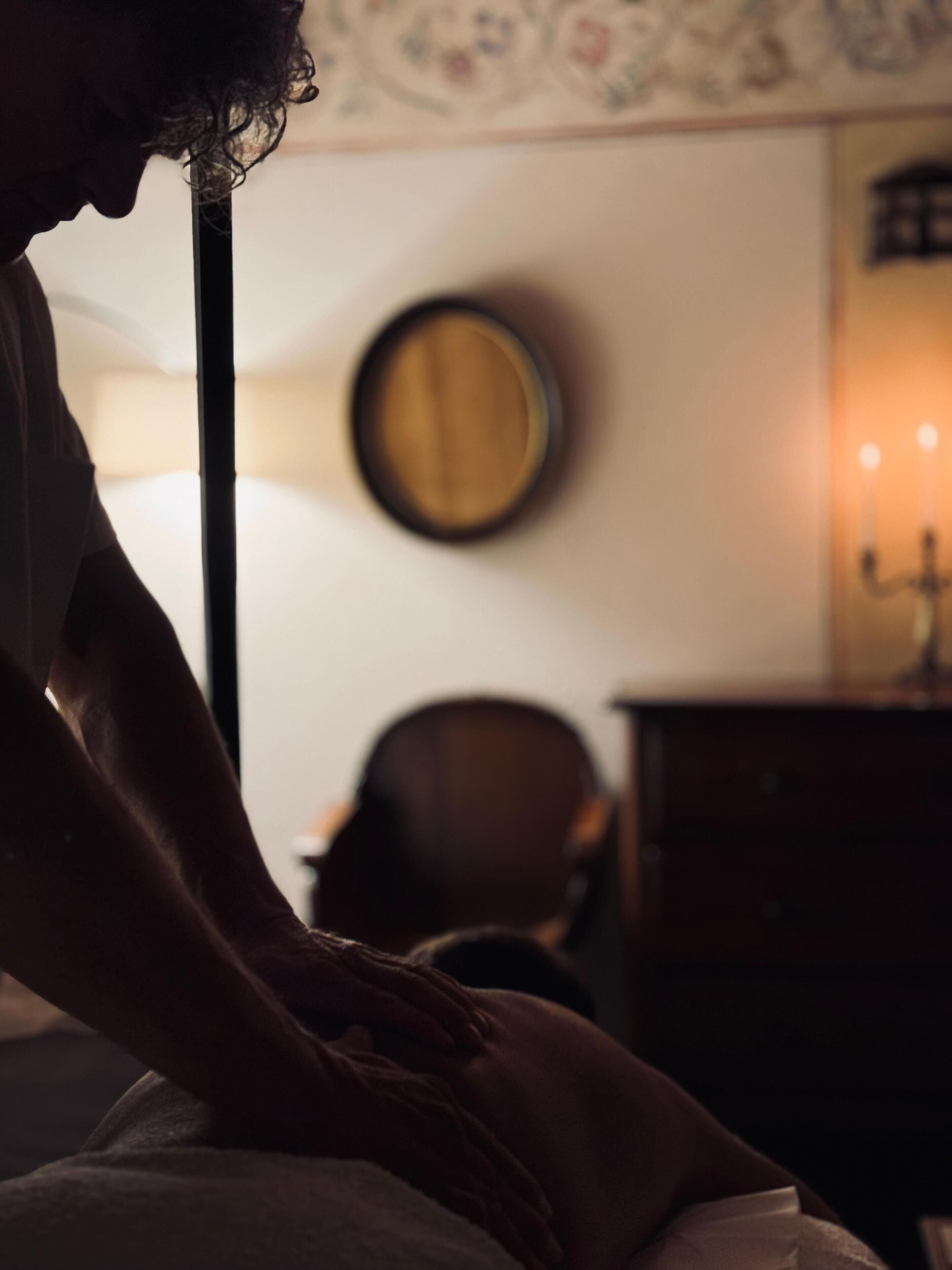 Une pièce faiblement éclairée, avec un lit, une chaise, une commode et un miroir fixé au mur.