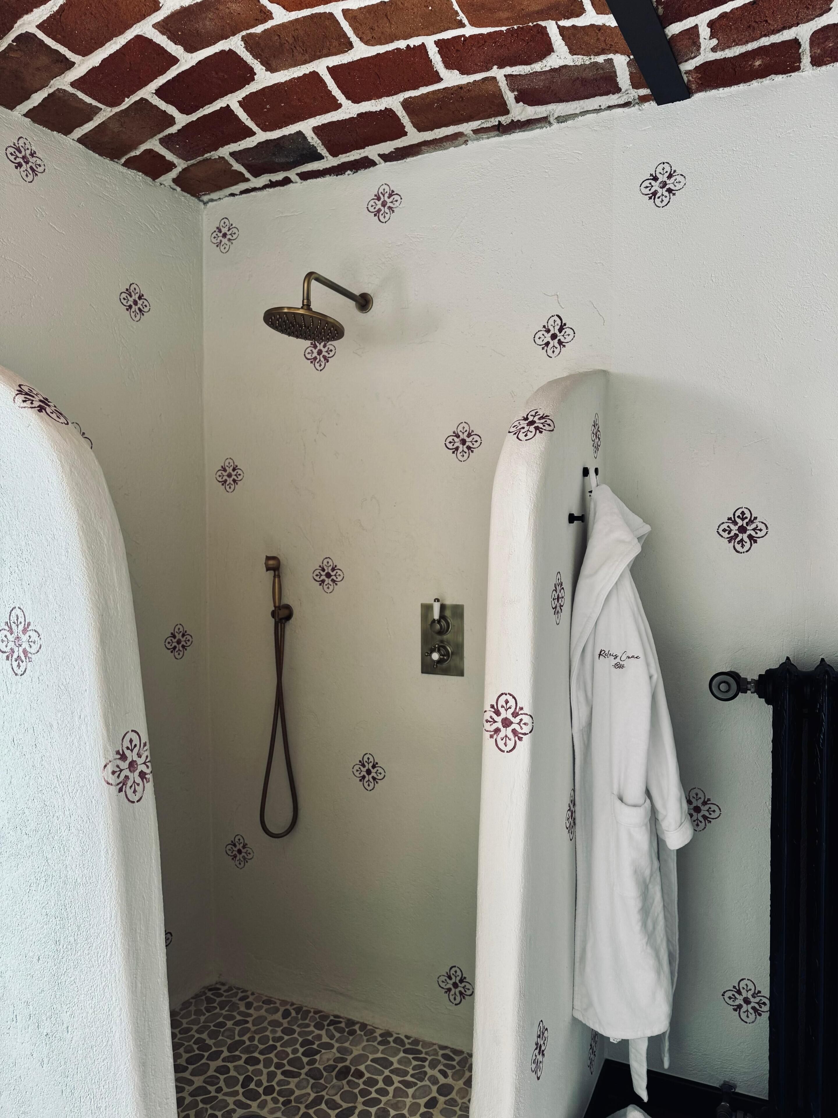 Une salle de bain avec une douche, un porte-serviettes et un peignoir accroché au mur.