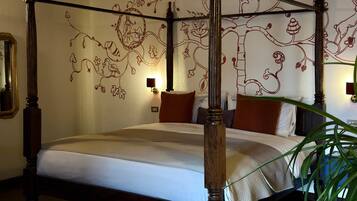 Een hemelbed met houten frame, plafond met baksteenmotief en een wand met bloemdecoratie.