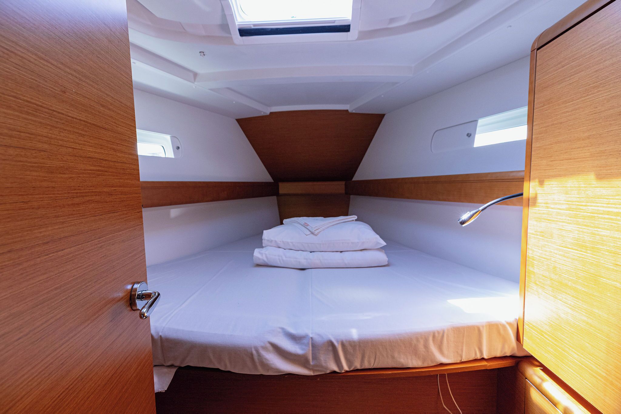 Una cabaña compacta con una cama individual, un ventanal pequeño y un tragaluz.