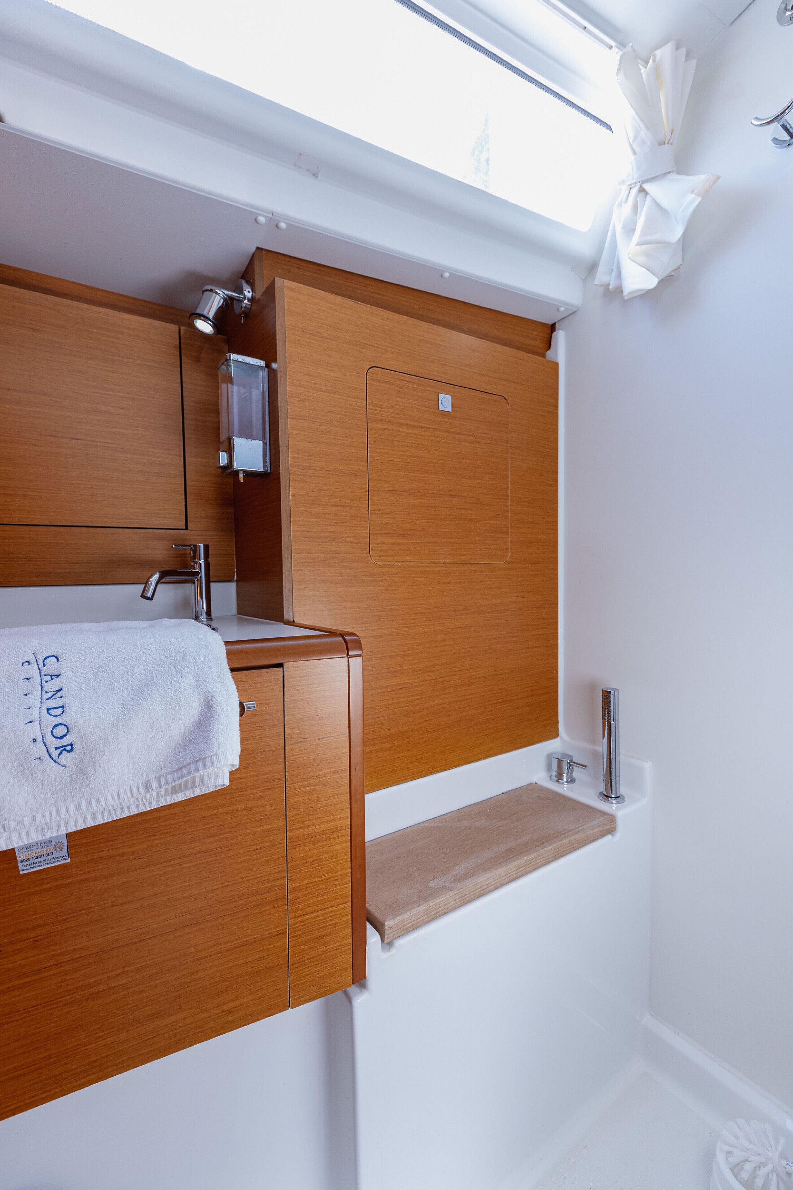 Une salle de bain avec un meuble-lavabo en bois, une serviette, un miroir et une fenêtre.