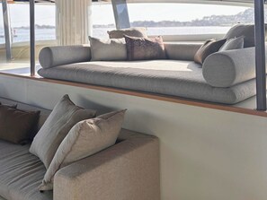 A modern interior with a sofa and cushions, a wooden bench, and a view of the water.