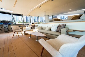A modern interior with a sofa, chairs, a coffee table, and a view of the city through large windows.