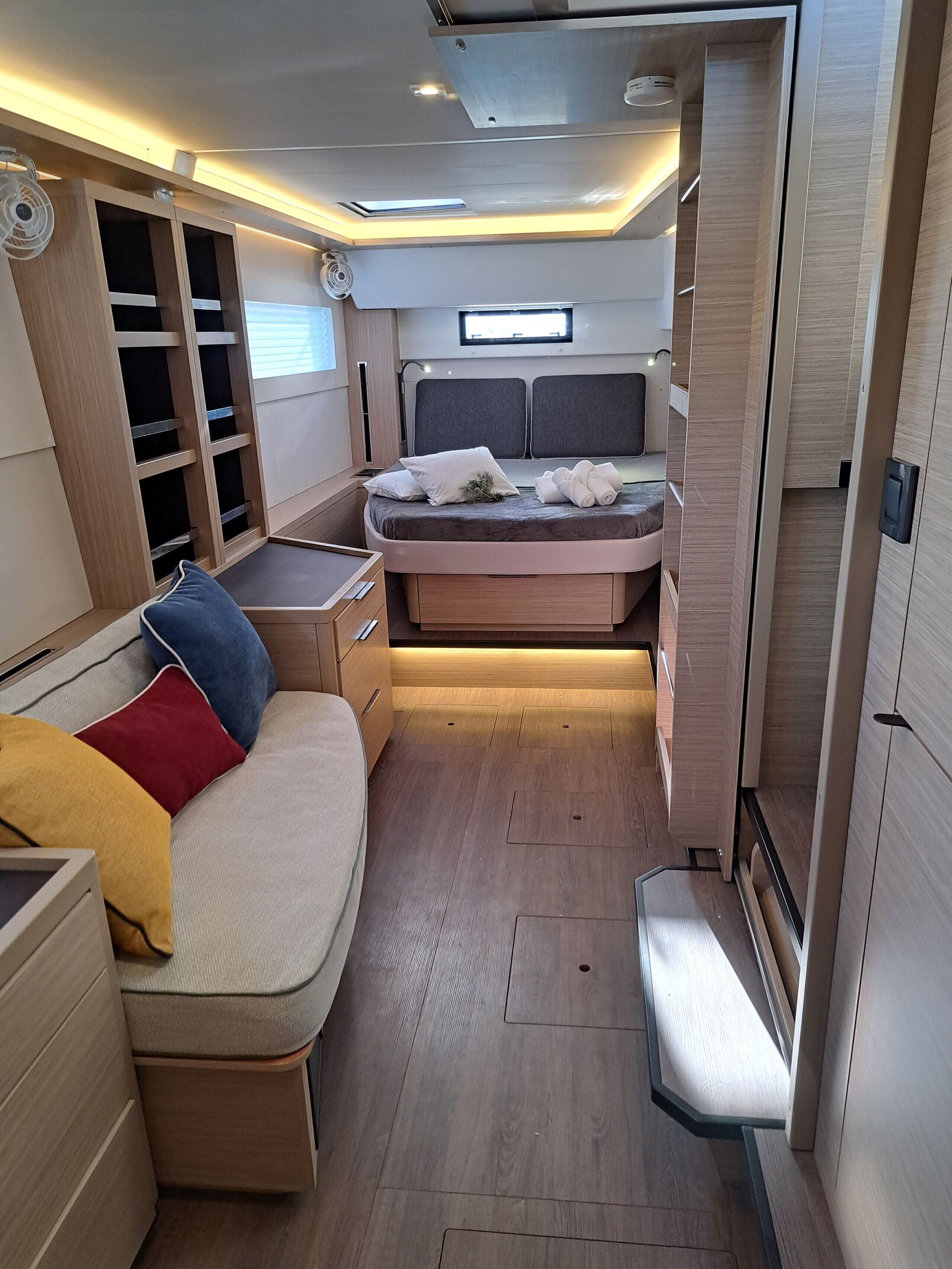 Un intérieur compact et bien éclairé, comprenant un lit, un coin salon et un espace de rangement.