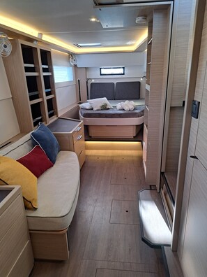 A compact, well-lit interior with a bed, a seating area, and a storage unit.