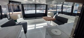 A boat interior with a seating area, a table, and a view of the outside.