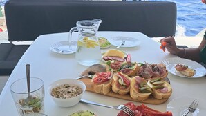 Ein gedeckter Tisch mit verschiedenen Gerichten, einer Karaffe und Blick auf das Meer.