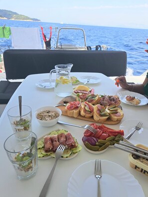 Ein gedeckter Tisch mit verschiedenen Gerichten, einer Karaffe und Blick auf das Meer.