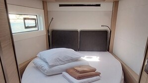 Ein kleines Schlafzimmer mit Oberlicht, einem Bett mit Kissen und einer zusammengelegten Decke sowie einem kleinen Fenster.