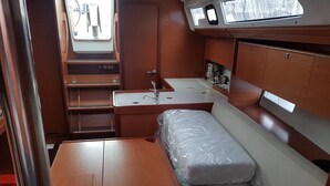 Espaço compacto com cama, uma mesinha, pia e janela.