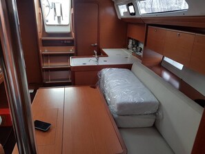 A compact interior with a bed, a small table, a sink, and a window. - Dubrovnik Delight: A Sun-Kissed Sailing Experience (Komolac)