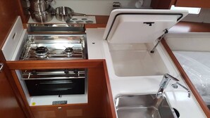 Uma kitchenette compacta com fogão, pia e gavetas para guardar.