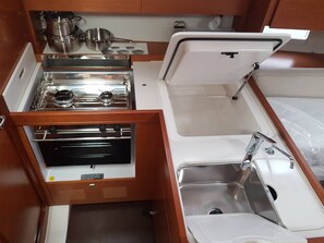Una kitchenette compacta con estufa, lavabo y cajones.