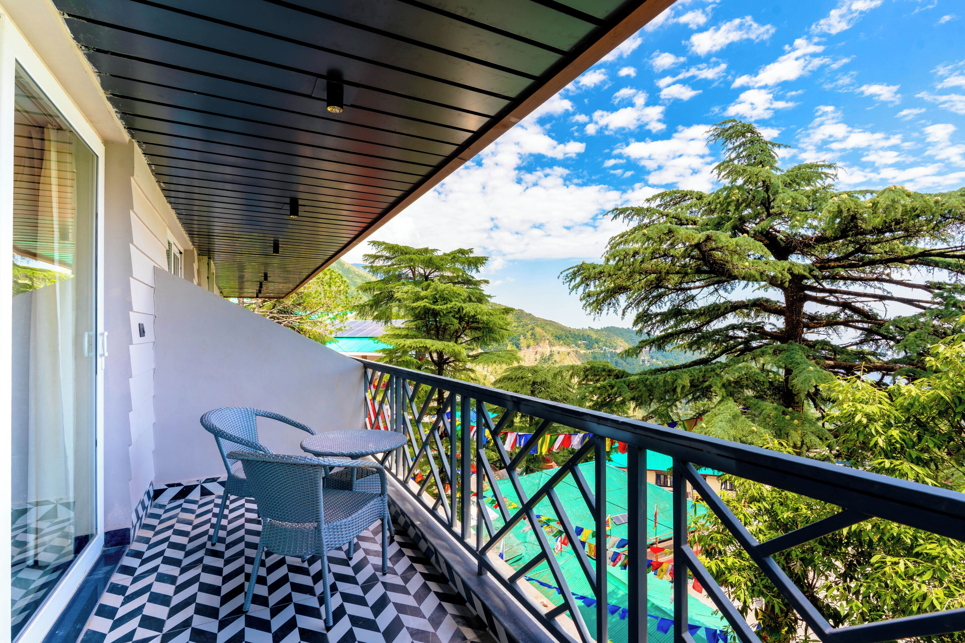 Un balcón con suelo estampado, una silla y barandilla con vistas a un paisaje montañoso.