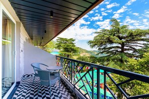 Un balcón con suelo estampado, una silla y barandilla con vistas a un paisaje montañoso.