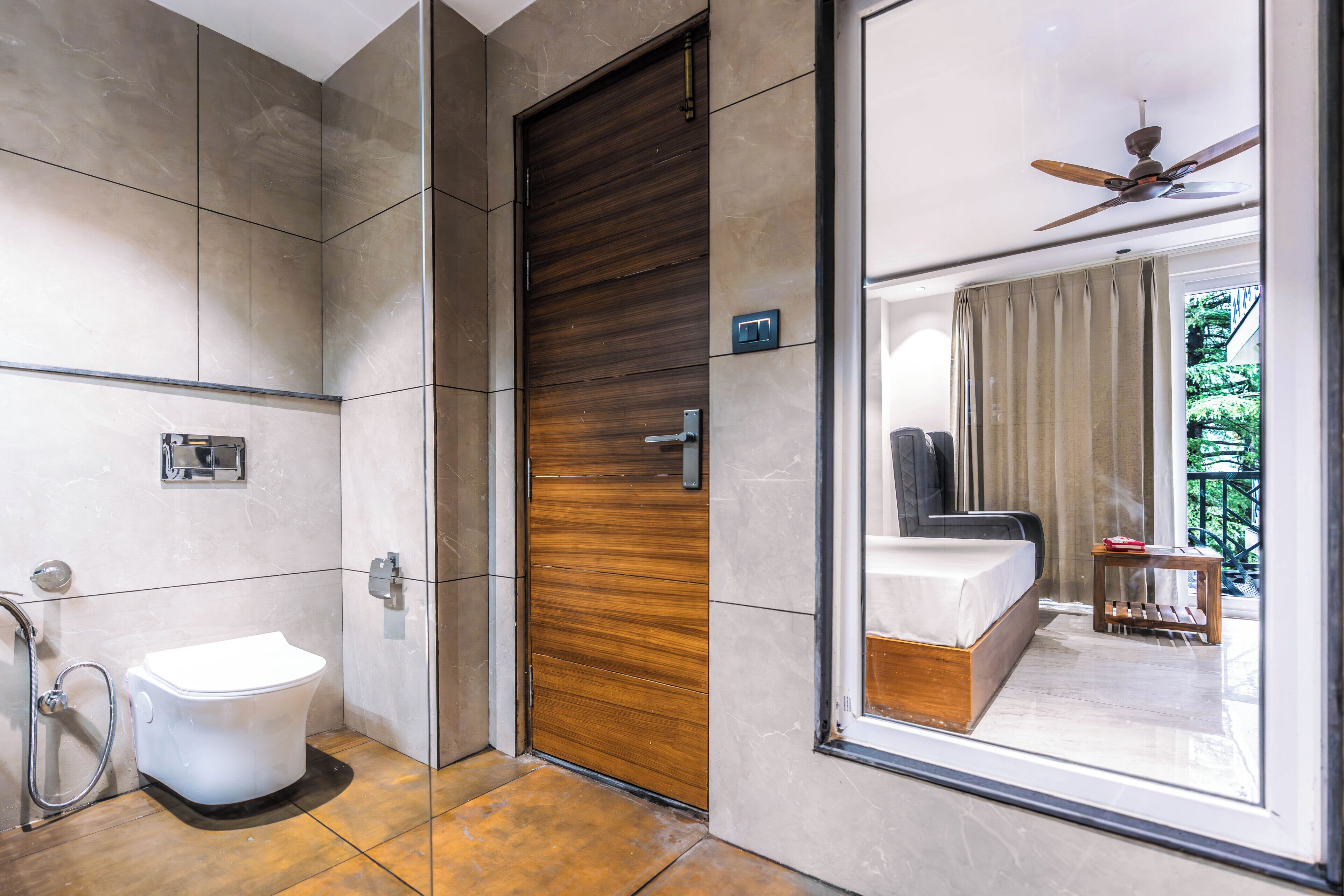 A modern bathroom with a toilet, a shower, and a wooden door.