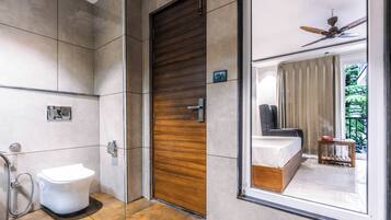 A modern bathroom with a toilet, a shower, and a wooden door.