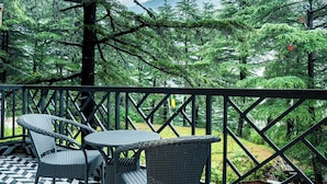 Eine Terrasse mit einem geometrisch gemusterten Boden, Gartenmöbeln und Blick auf ein bewaldetes Gebiet.