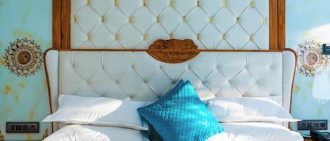 Een bed met een gestoffeerd hoofdeinde, witte beddengoed en een blauw accentkussen.